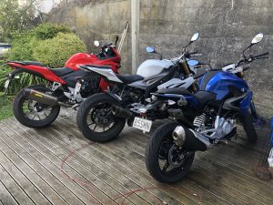 Honda CBR500R, BMW S1000R, and BMW G310R motorcycles parked on a wooden deck.