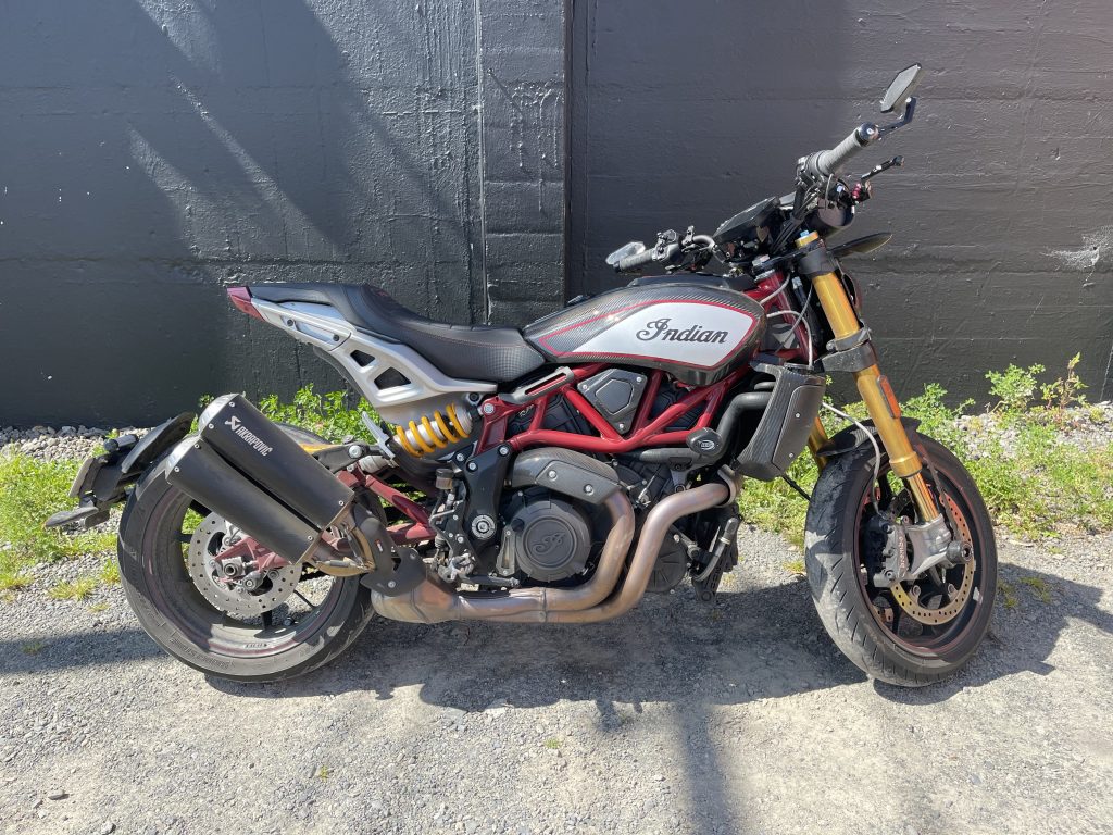 An Indian FTR 1200 motorcycle parked in front of a brick wall.